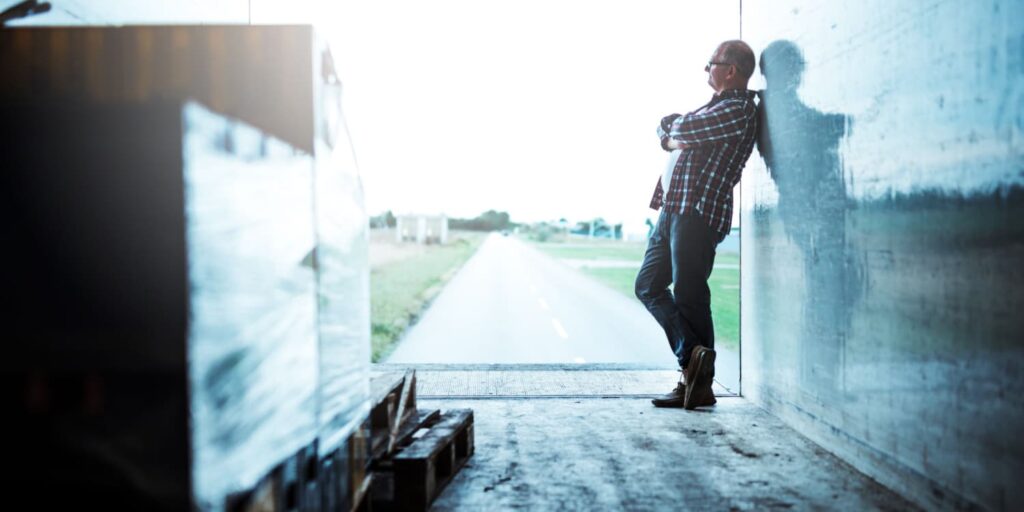 A trucker in the back of a trailer, who may have used a truck driver packing list to prepare for his haul